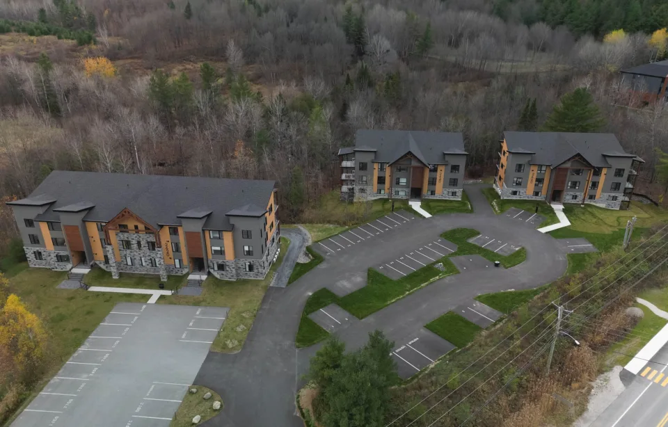 Trois édifices à condos, trois étages, look contemporain, construction neuve, vue aériene dans un espace boisé à l'automne